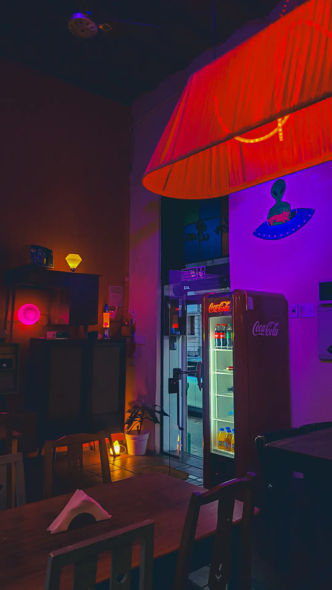 Ambiente nocturno con iluminación cálida roja, mesas y sector de barra en Digno