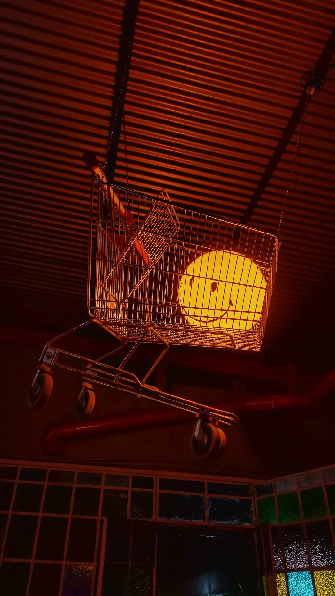 Instalación de arte contemporáneo con carrito de compras y luces cálidas en el techo
