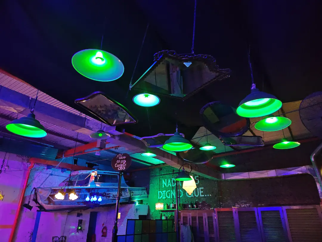 Detalle de lámparas colgantes retro industriales con luces verdes en el techo del bar