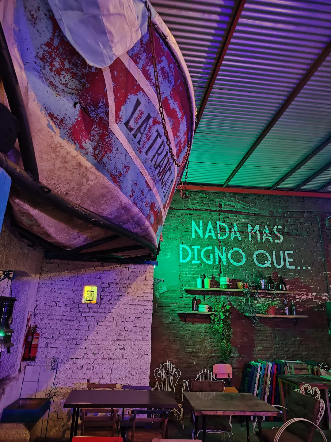 Mural con frase 'Nada más digno que' y mesas en el patio exterior de Digno