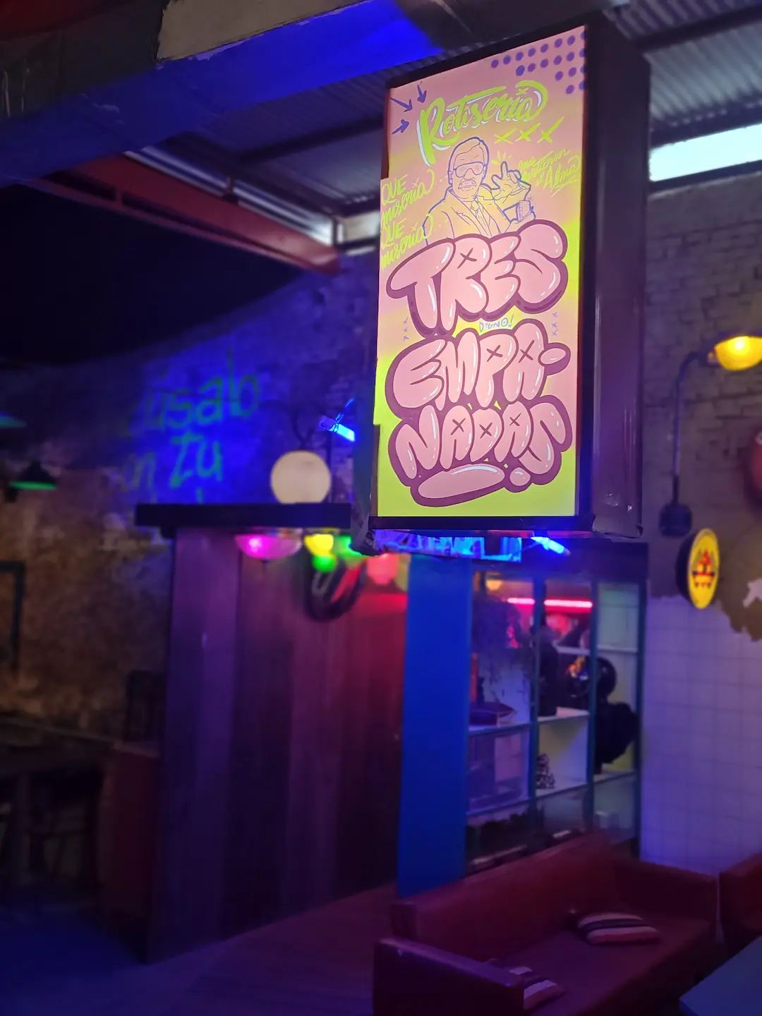 Pasillo ambientado con luces de neón rosa y violeta en Digno Bar