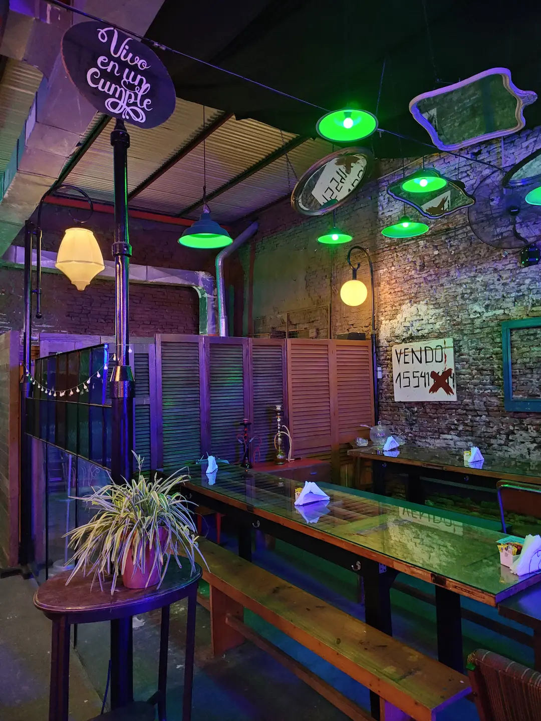 Patio cervecero con mesas comunitarias de madera y vegetación en Digno Barrio Martín