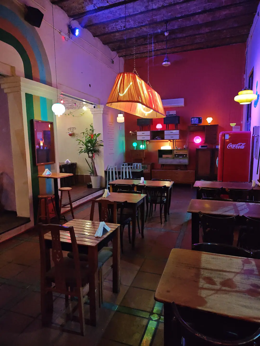 Vista en perspectiva del salón gastronómico con mesas de madera y lámparas cálidas