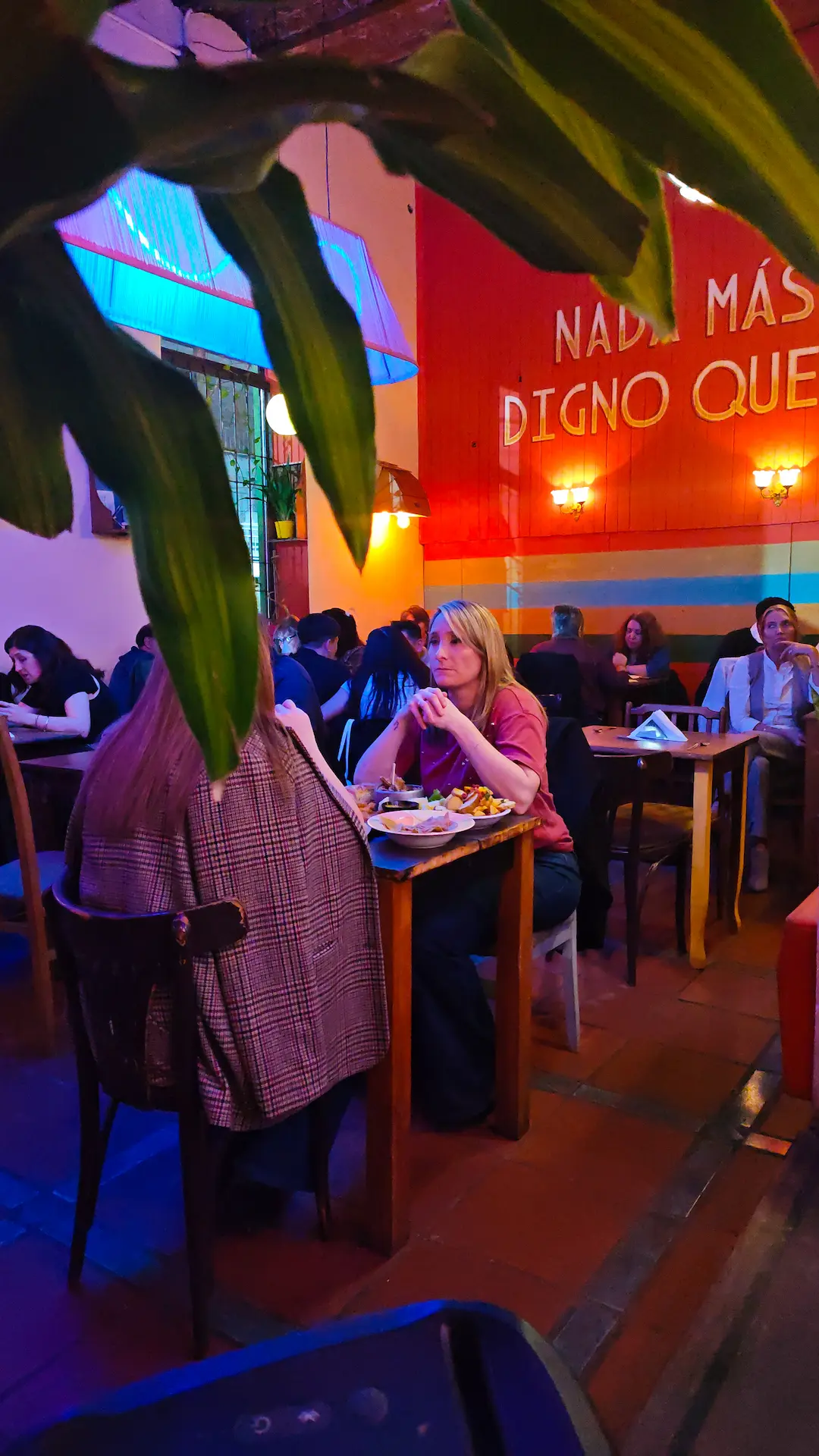 Salón concurrido con grupos compartiendo mesas y tragos bajo luces cálidas