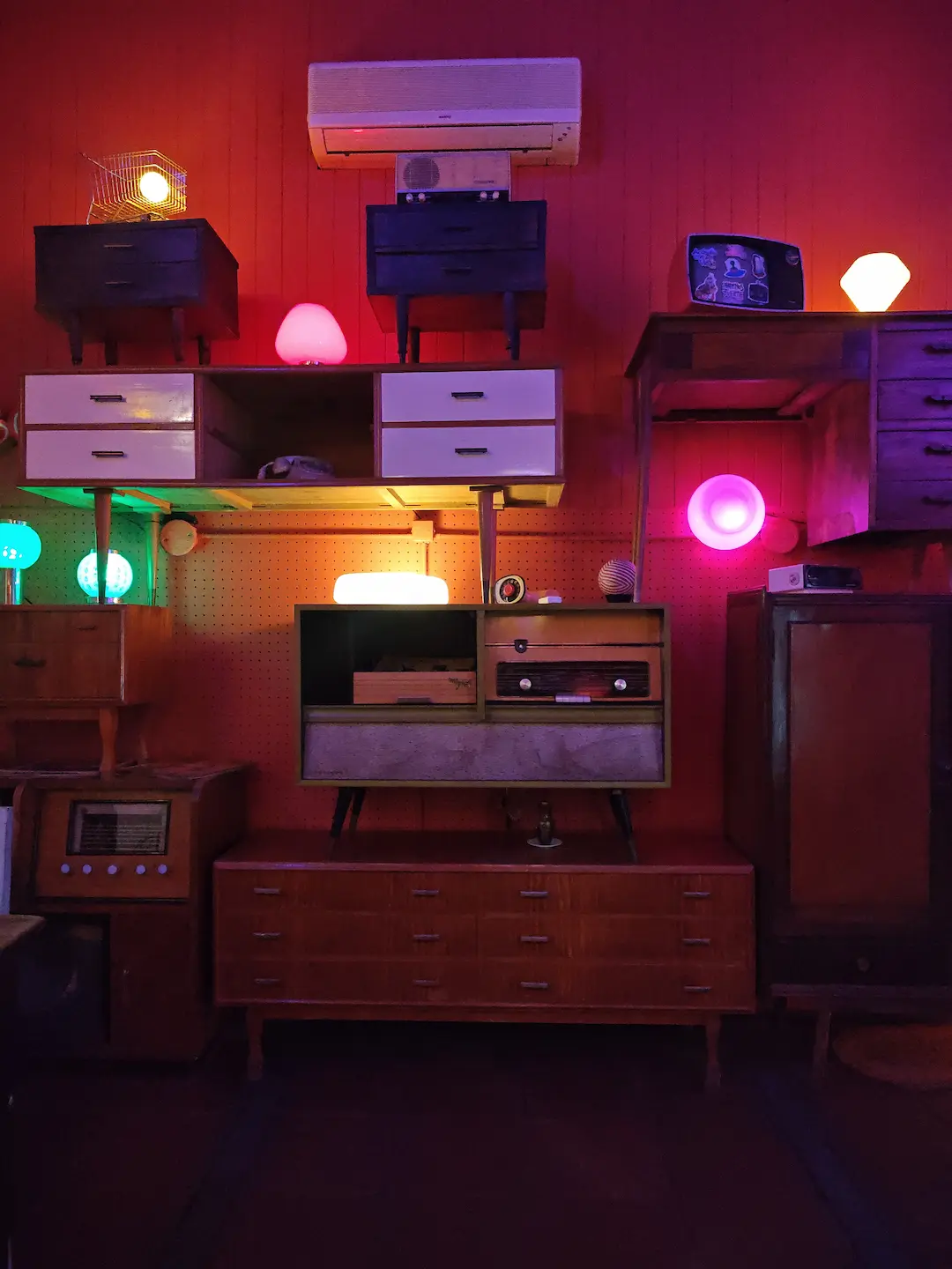Instalación retro con aparadores de época, televisores antiguos y luces ambientales