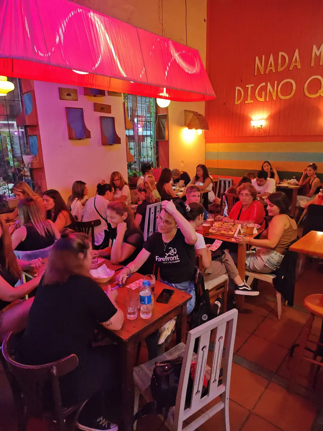 Salón concurrido con grupos compartiendo mesas y tragos bajo luces cálidas